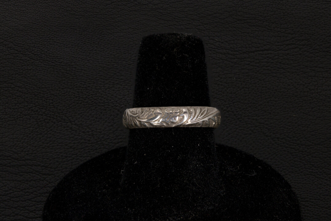 Silver ring with a central oval Opal on a black stand against a dark background back view
