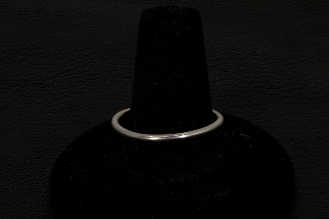 Small dark base opal ring set in sterling silver on a black stand on a black background band view only
