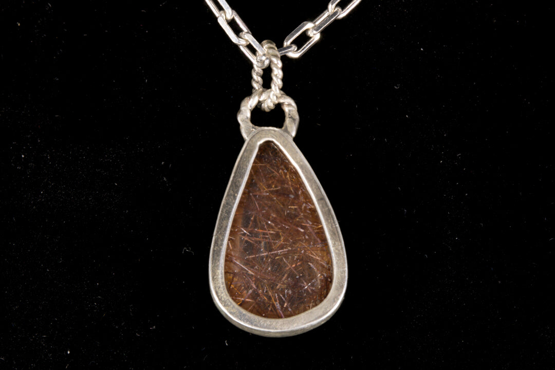 Golden Rutile in clear Quartz and bezel set in sterling silver on a black background back view
