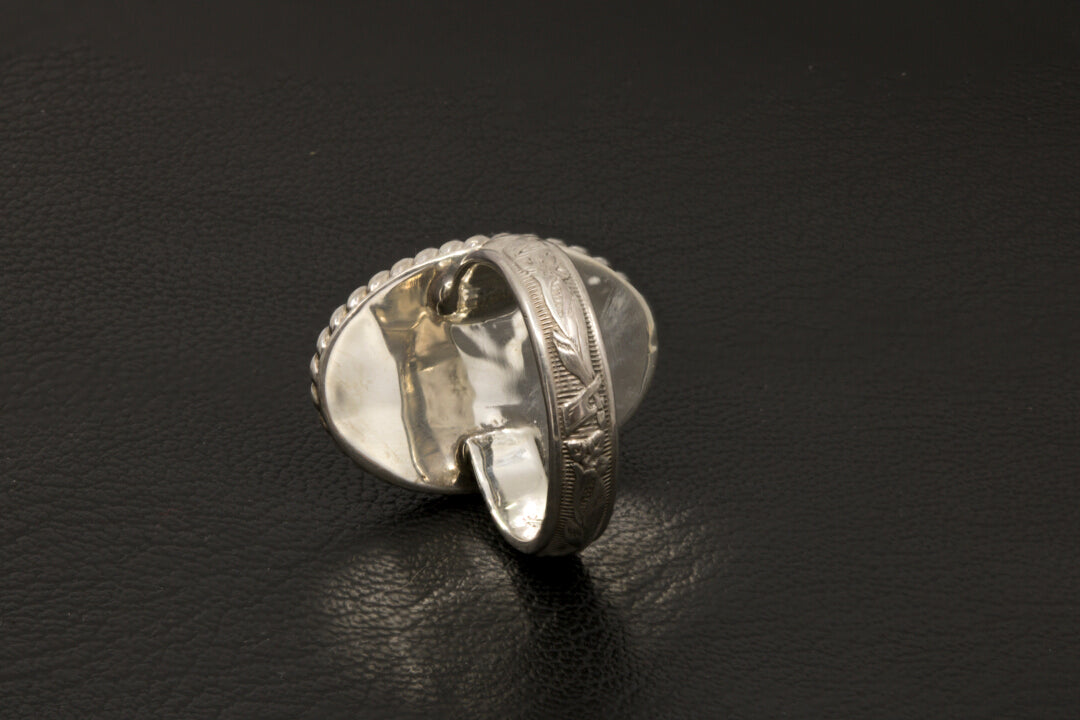 Silver ring with intricate design on a black background back view