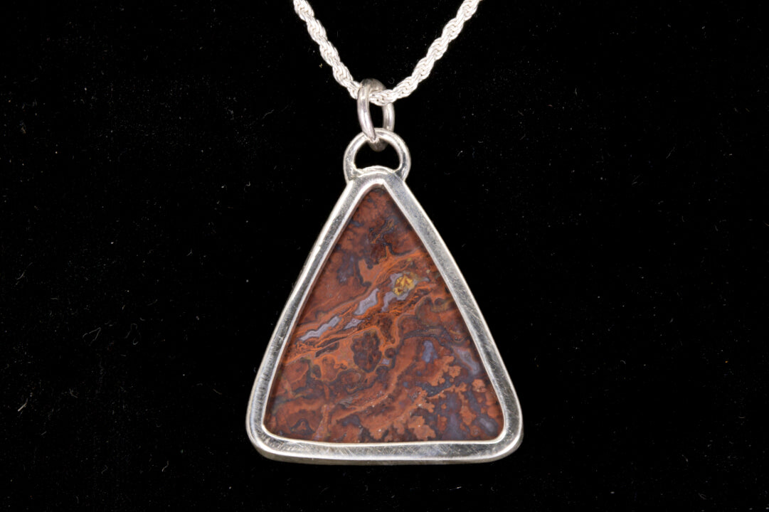Rooster Tail Agate Triangle Pendant set in sterling silver on a black background open back view