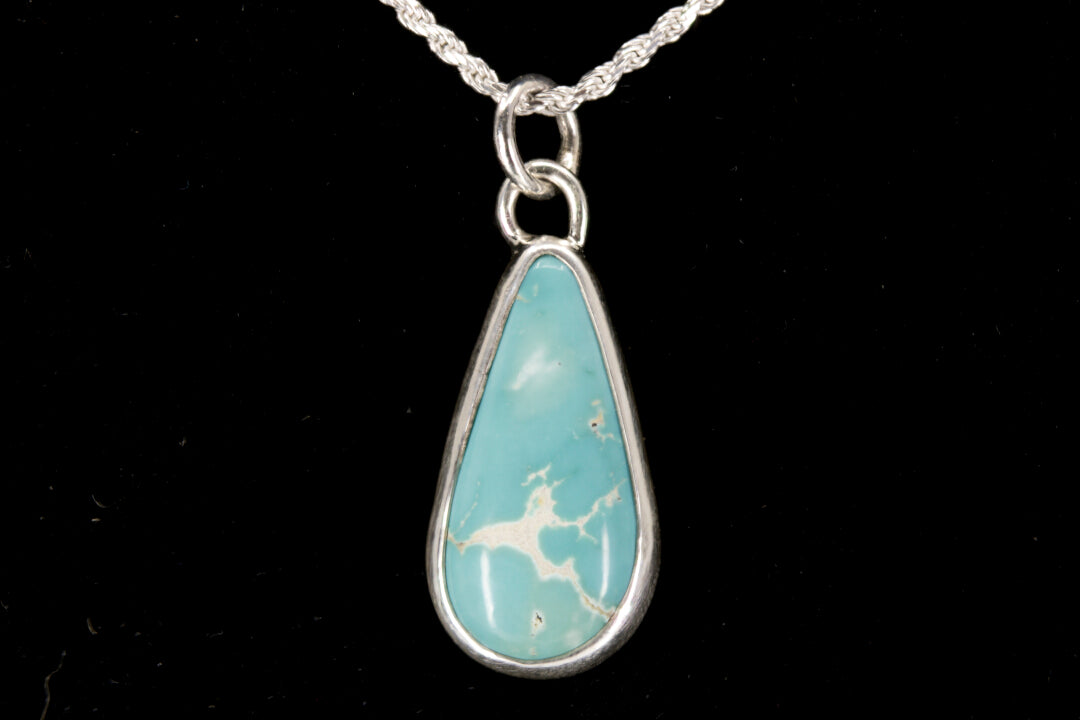 Teardrop-shaped pendant with blue stone and silver frame on a black background front view