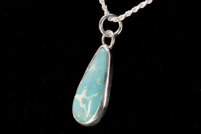 Necklace with a blue teardrop pendant on a black background left side view