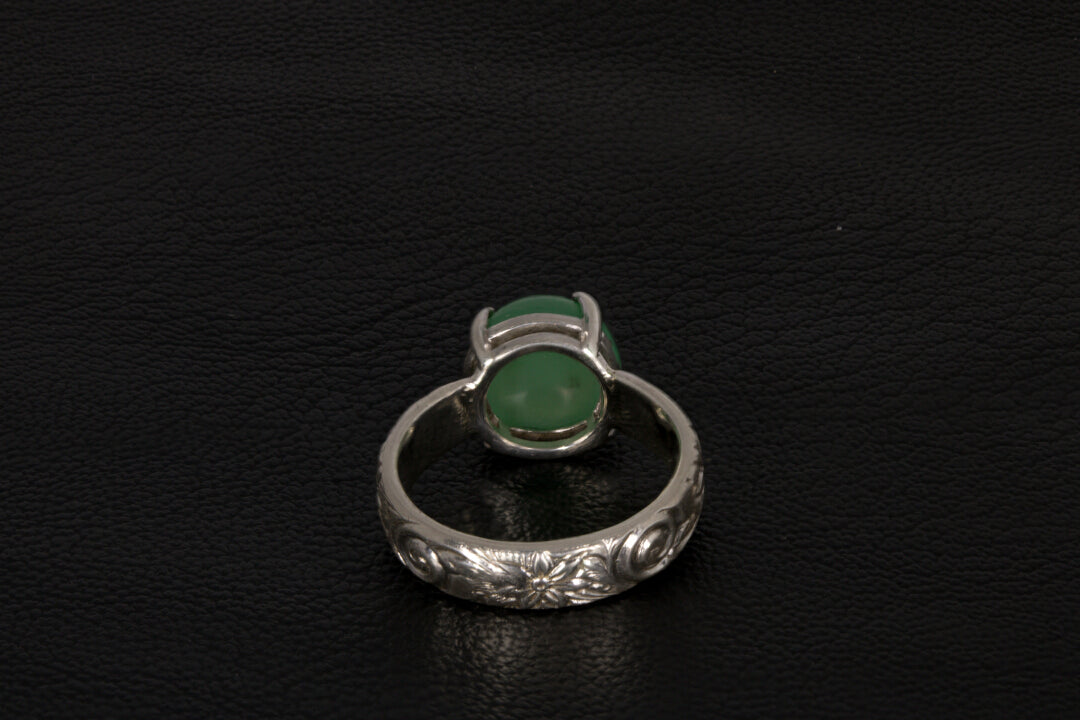 Silver ring with a green gemstone back view a dark background