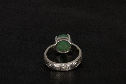 Silver ring with a green gemstone back view a dark background