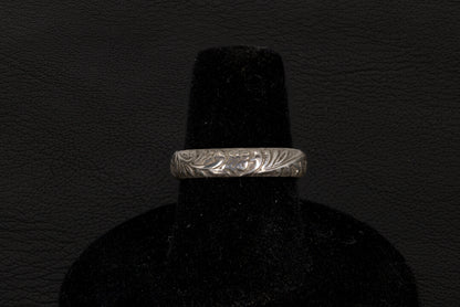Silver ring with a central oval Opal on a black stand against a dark background back view