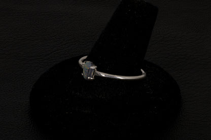 Small dark base opal ring set in sterling silver on a black stand on a black background