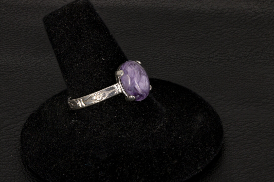 Purple charoite Ring, prong set in sterling silver on a black stand