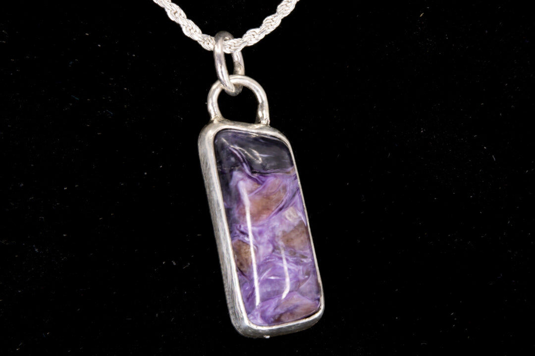 Charoite Rectangle With Dark Purple Cap Set In Sterling Silver on black background, left side view.
