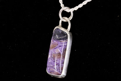 Charoite Rectangle With Dark Purple Cap Set In Sterling Silver on black background, right side view.