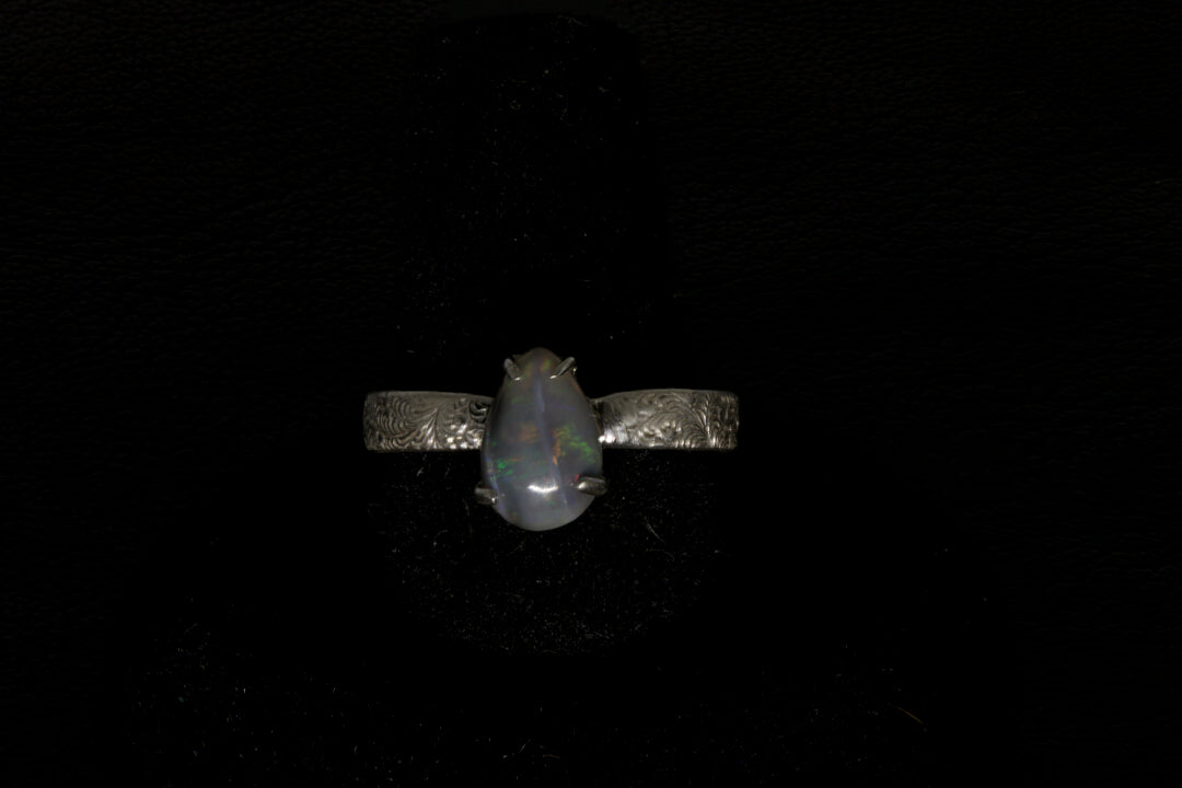 Ring with a pear-shaped opal stone on a dark background
