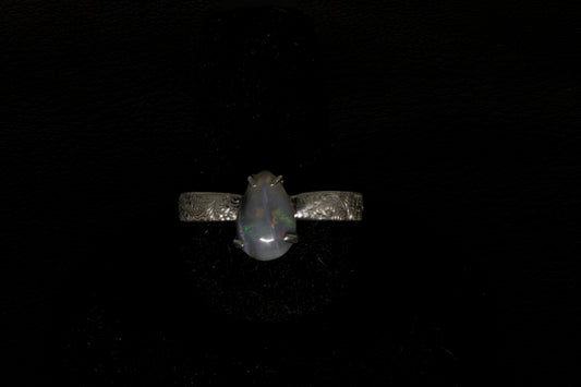 Ring with a pear-shaped opal stone on a dark background
