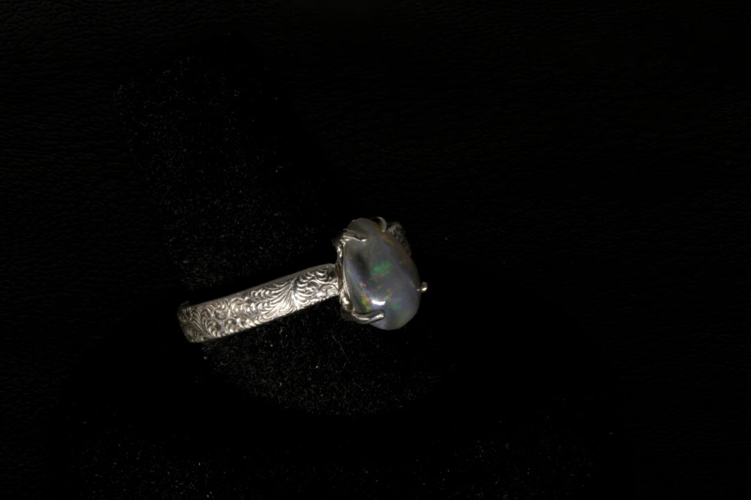 Silver ring with a central gemstone on a dark textured surface