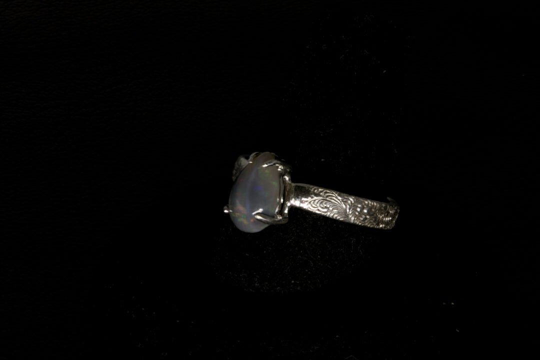 Silver ring with a central gemstone on a black background