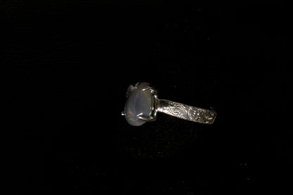 Silver ring with a central gemstone on a black background