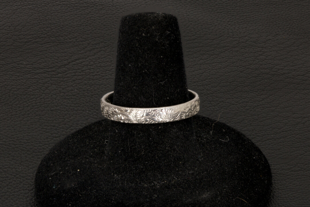 Silver bracelet on a black velvet stand against a dark background back view