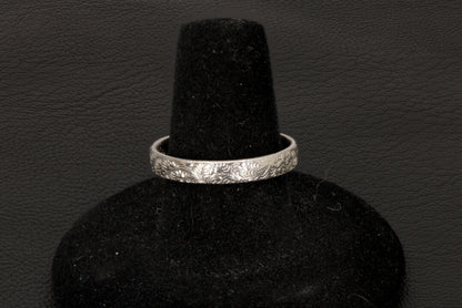 Silver bracelet on a black velvet stand against a dark background back view