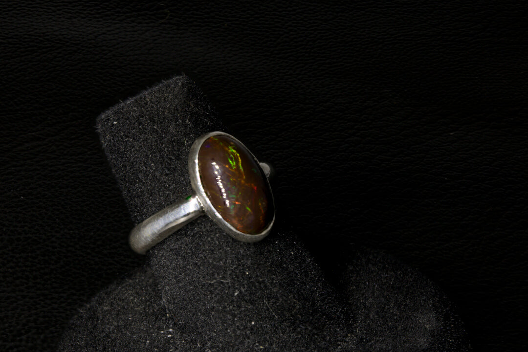 Silver ring with a dark stone on a black background
