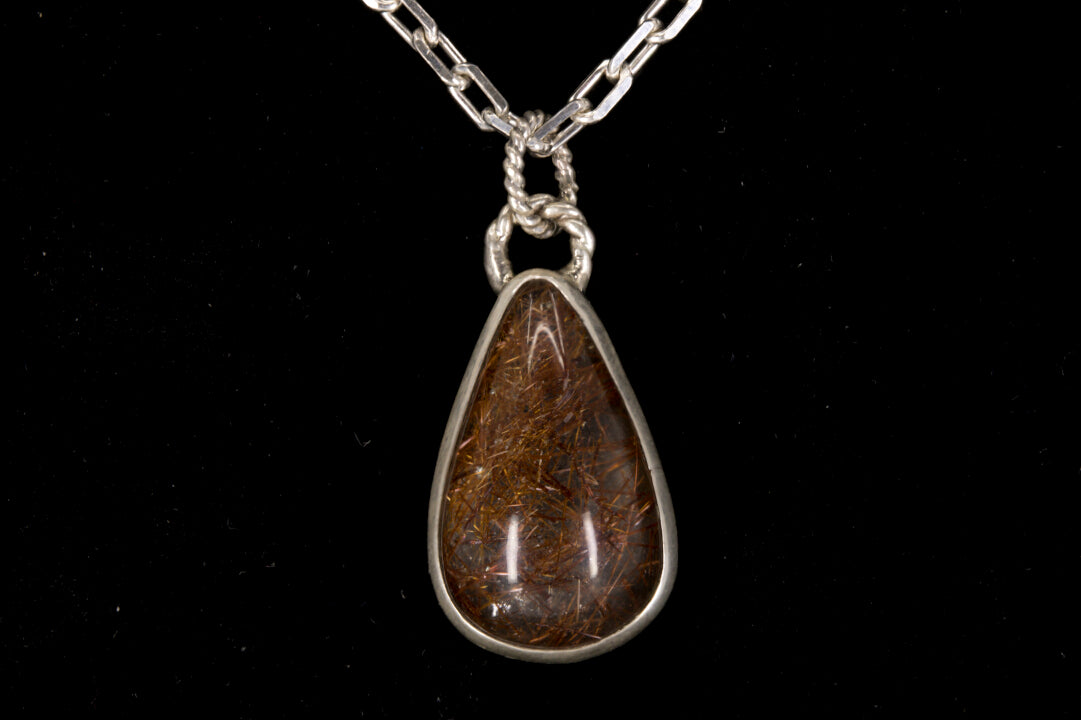 Golden Rutile in clear Quartz and bezel set in sterling silver on a black background