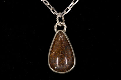 Golden Rutile in clear Quartz and bezel set in sterling silver on a black background