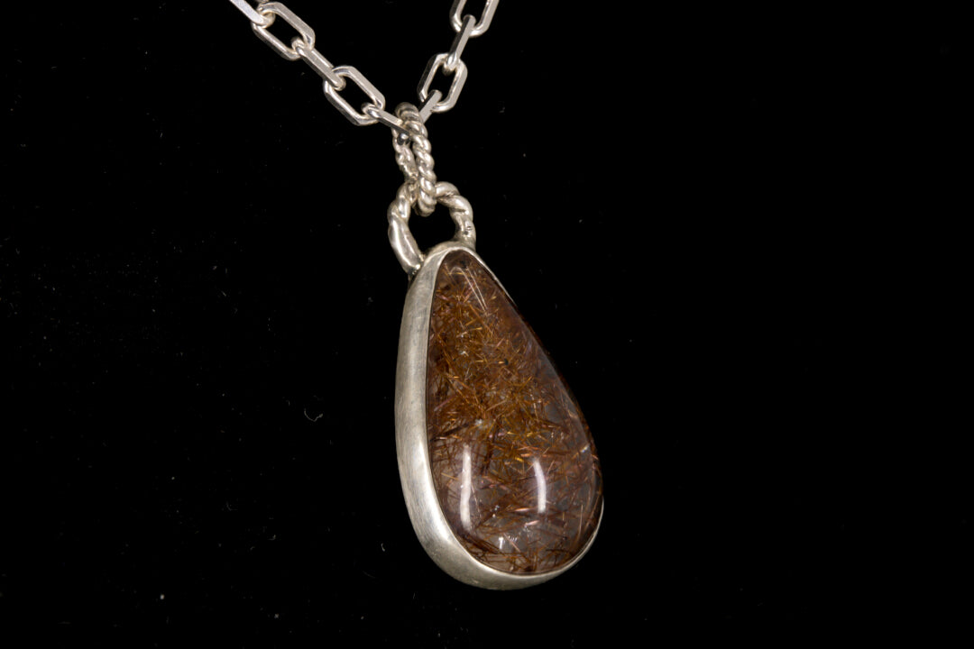 Golden Rutile in clear Quartz and bezel set in sterling silver on a black background