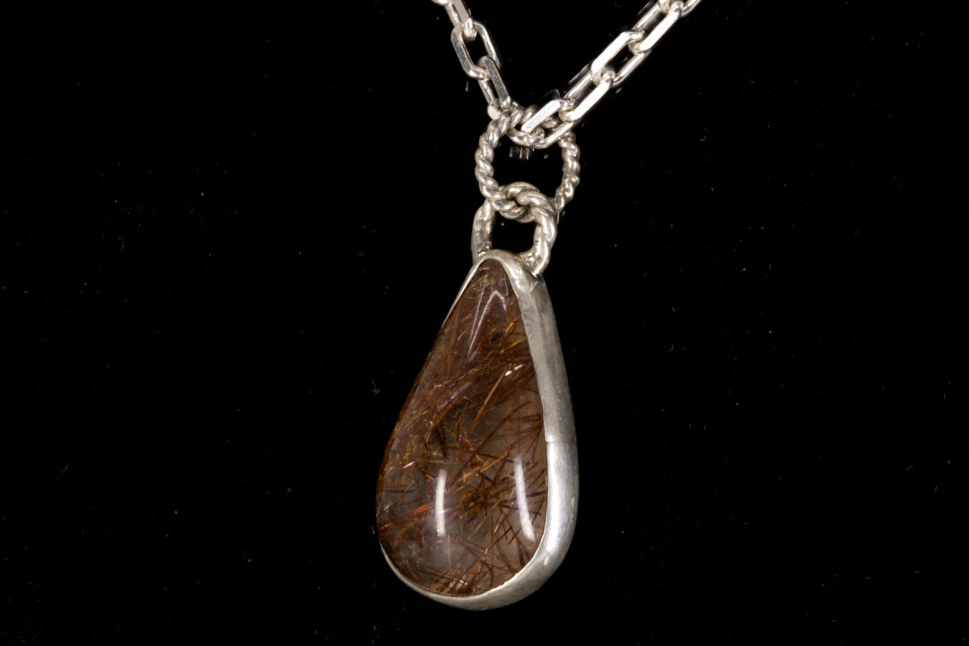 Golden Rutile in clear Quartz and bezel set in sterling silver on a black background