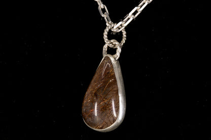 Golden Rutile in clear Quartz and bezel set in sterling silver on a black background