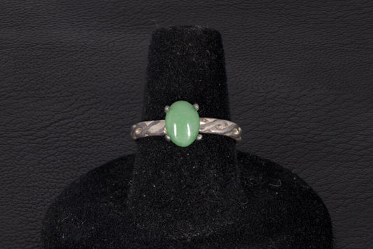 Green Jade ring set in sterling silver with a decorative infinity ring band on a black stand