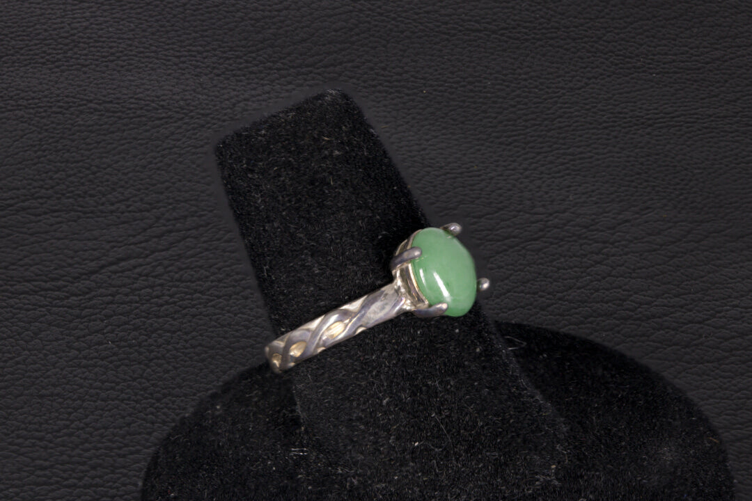 Green Jade ring set in sterling silver with a decorative infinity ring band on a black stand