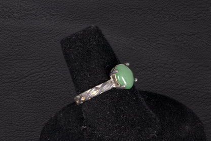 Green Jade ring set in sterling silver with a decorative infinity ring band on a black stand