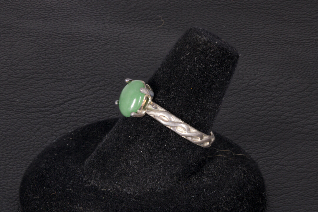 Green Jade ring set in sterling silver with a decorative infinity ring band on a black stand