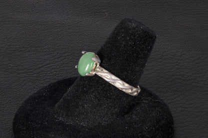 Green Jade ring set in sterling silver with a decorative infinity ring band on a black stand