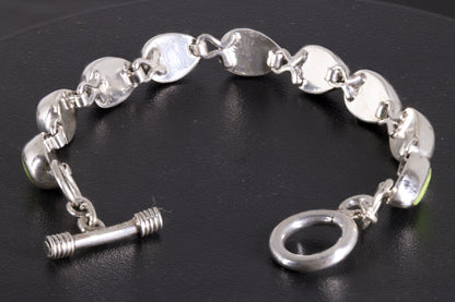 link-style bracelet with nine green teardrop cabochons linked together on a black background back side