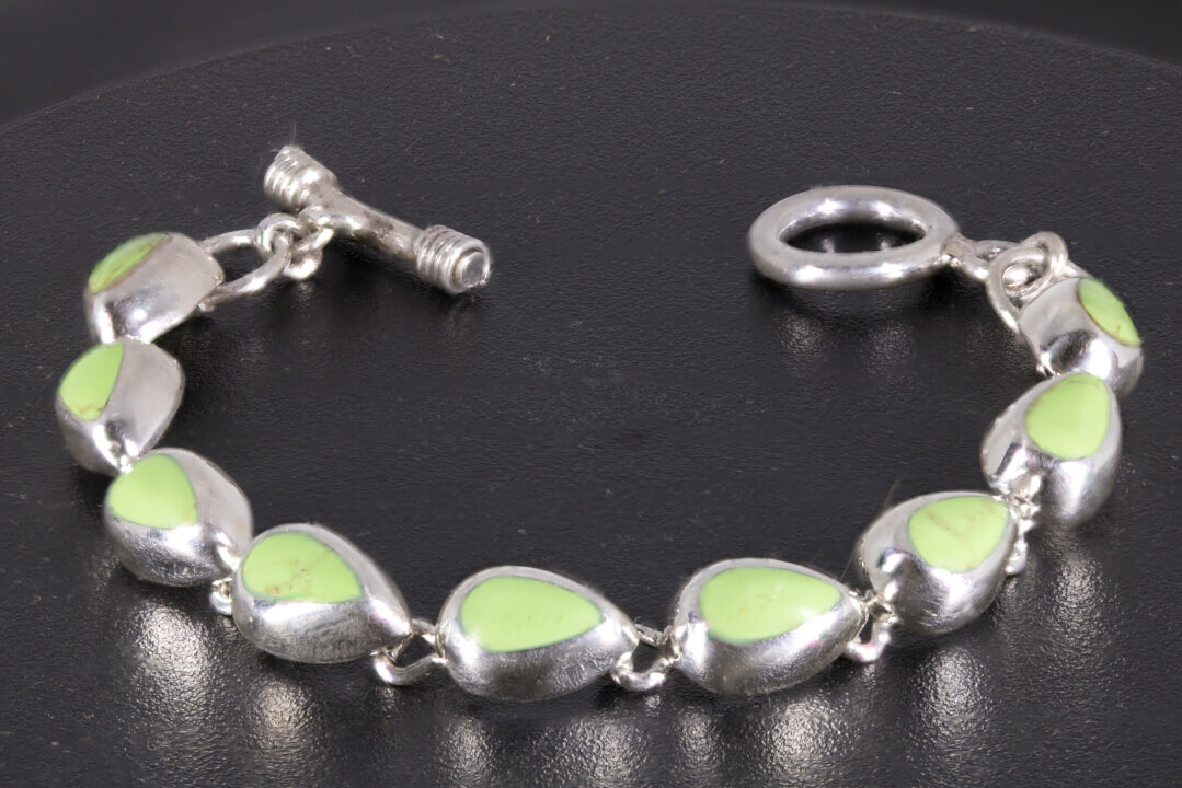 link-style bracelet with nine green teardrop cabochons linked together on a black background