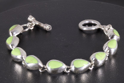 link-style bracelet with nine green teardrop cabochons linked together on a black background