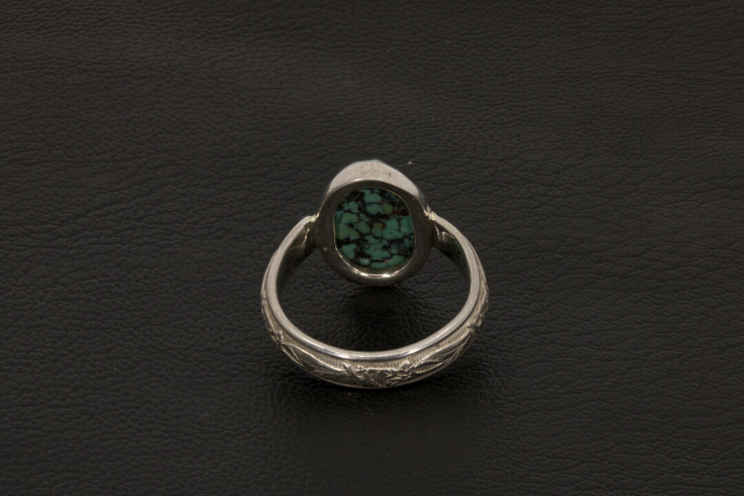 Oval Turquoise ring set in sterling silver on a black stand on a black background back view