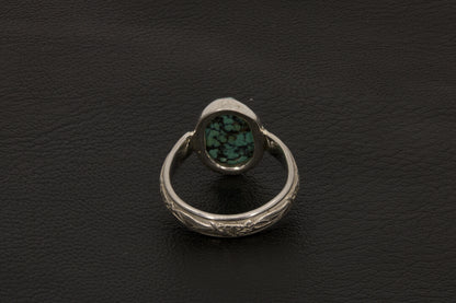 Oval Turquoise ring set in sterling silver on a black stand on a black background back view