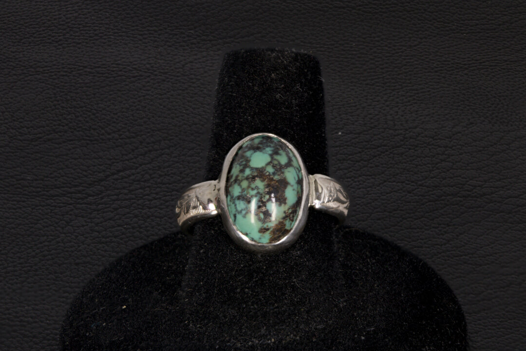 Oval Turquoise ring set in sterling silver on a black stand on a black background