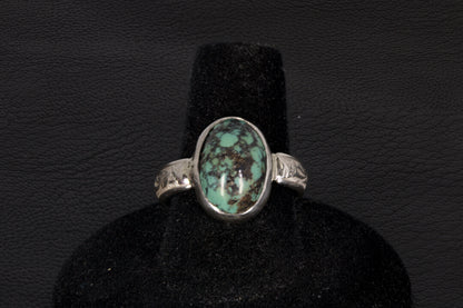 Oval Turquoise ring set in sterling silver on a black stand on a black background