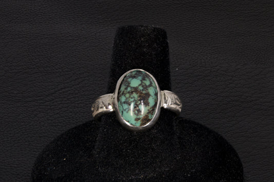 Oval Turquoise ring set in sterling silver on a black stand on a black background