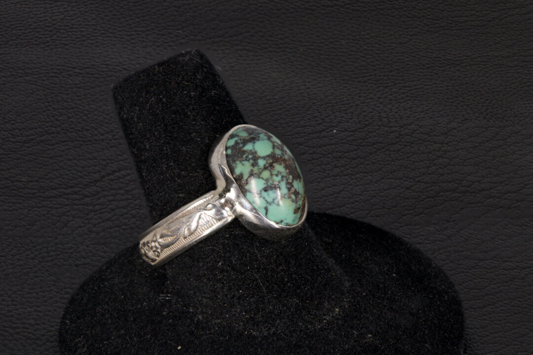 Oval Turquoise ring set in sterling silver on a black stand on a black background
