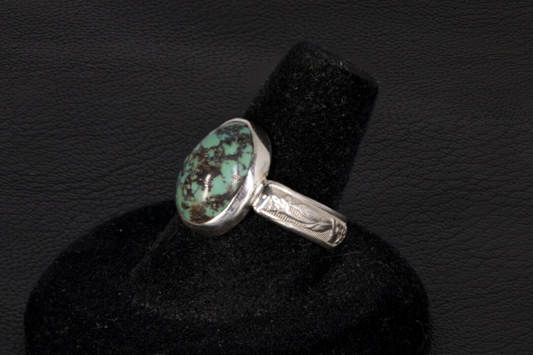 Oval Turquoise ring set in sterling silver on a black stand on a black background