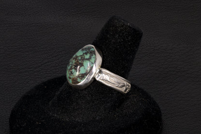 Oval Turquoise ring set in sterling silver on a black stand on a black background