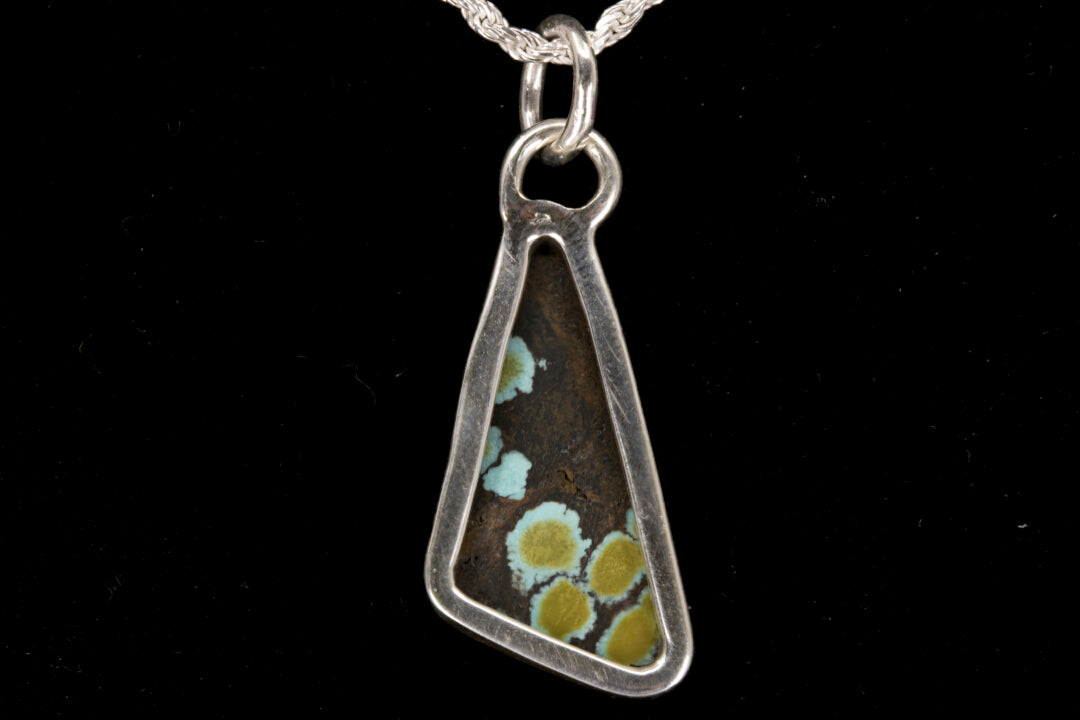 Triangular pendant with natural pattern on a black background back view