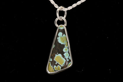 Triangular pendant with a natural pattern on a black background front view