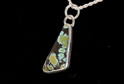 Necklace with a pendant featuring a natural pattern on a black background left side view