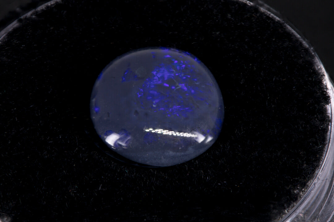 Lightning Ridge Black Opal with purple flash on a black background