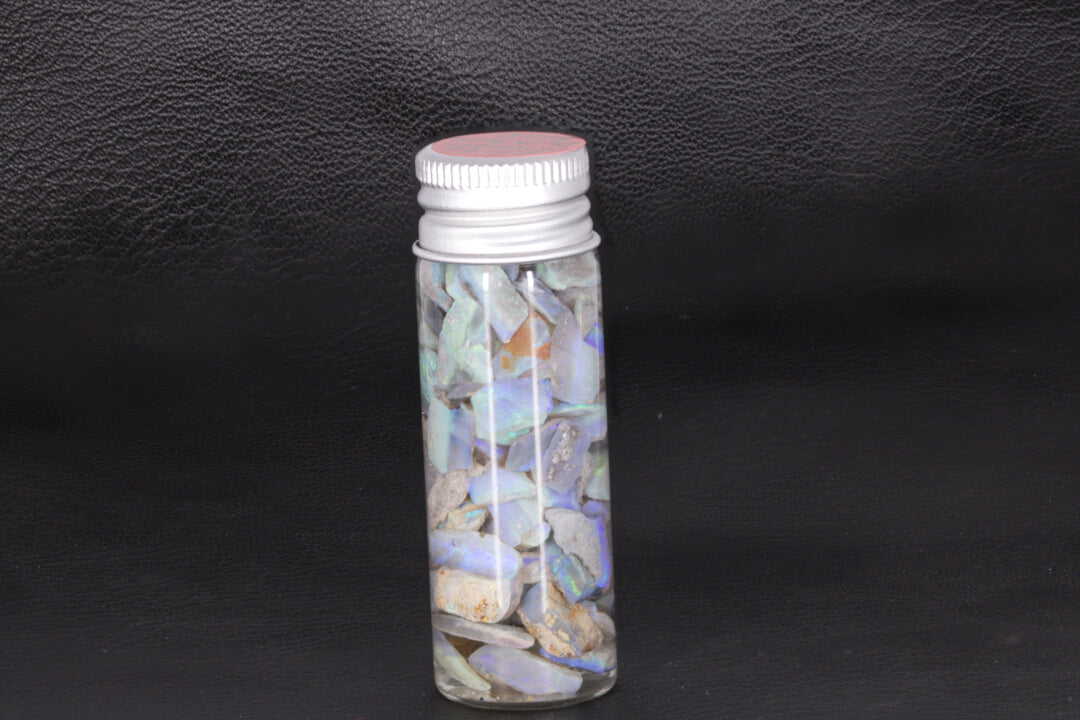 Mintabie dark base opal rough chips and small stones in a jar