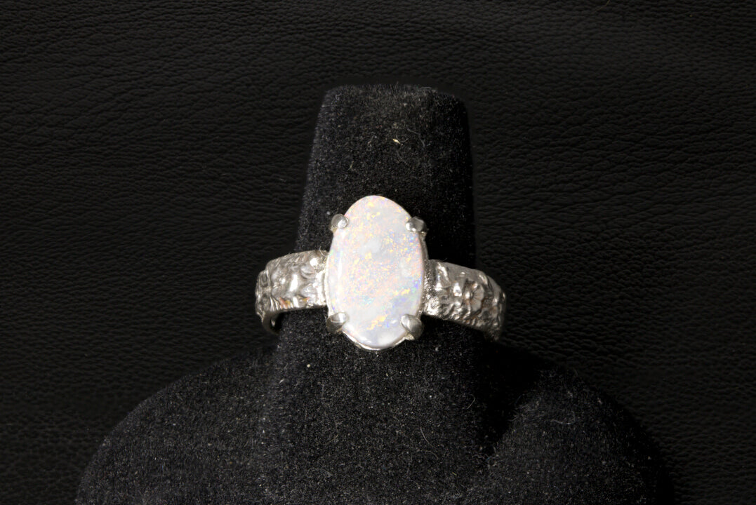 Silver ring with a large Opal gemstone on a black stand