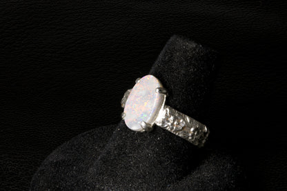 Silver ring with a large Opal gemstone on a black stand